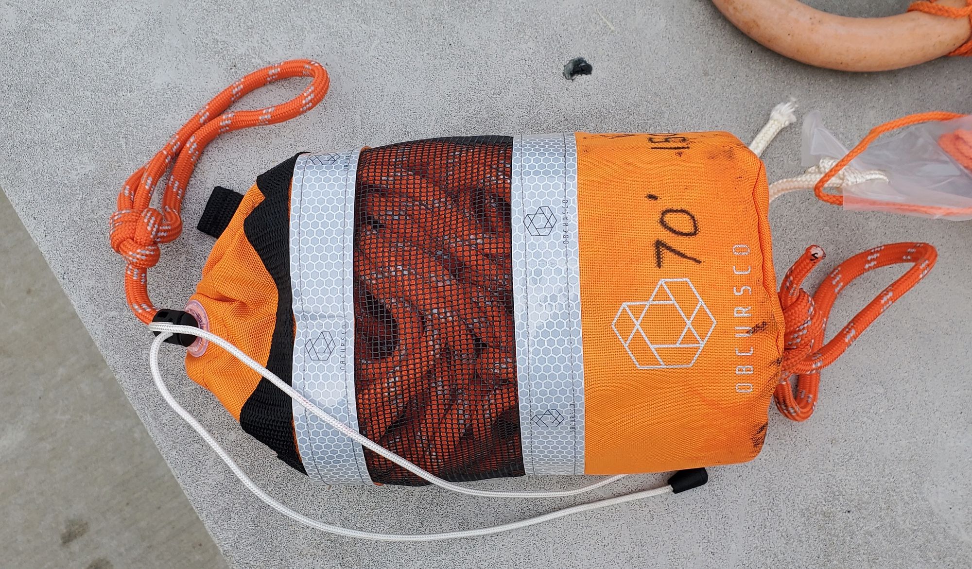 An orange mesh and fabric bag containing 70' of orange safety rope