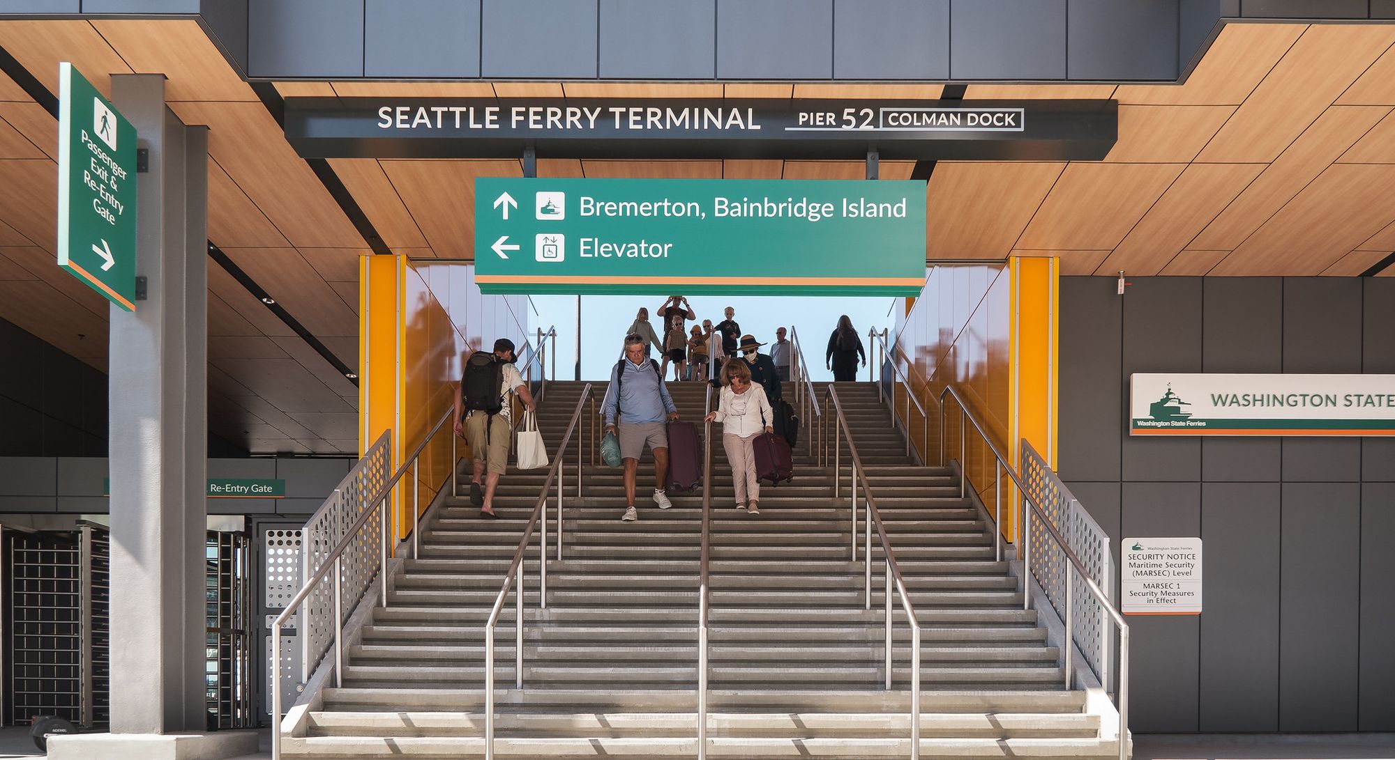 Passengers walk down a flight of stairs in a newly constructed building with ferry signs.