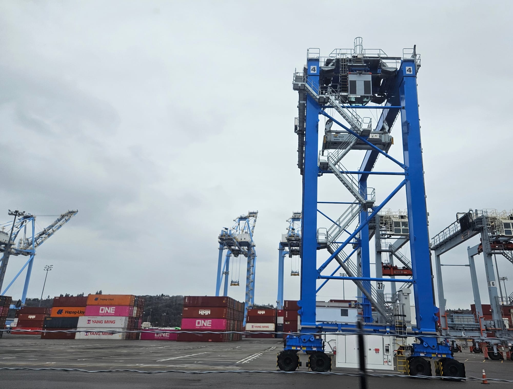 A tall blue vehicle with a lift to pick up shipping containers. 