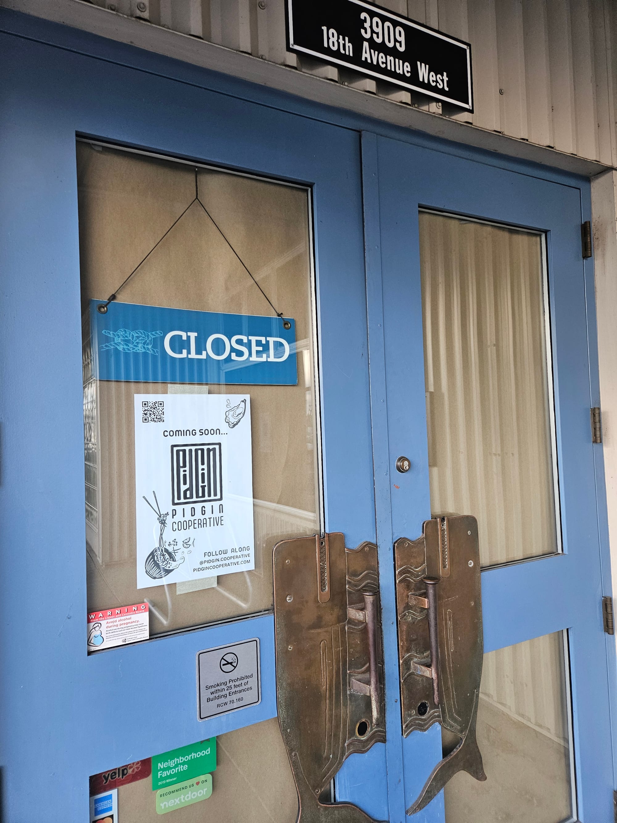 A "Closed" sign and a "Coming soon" sign in a window with blue trim.