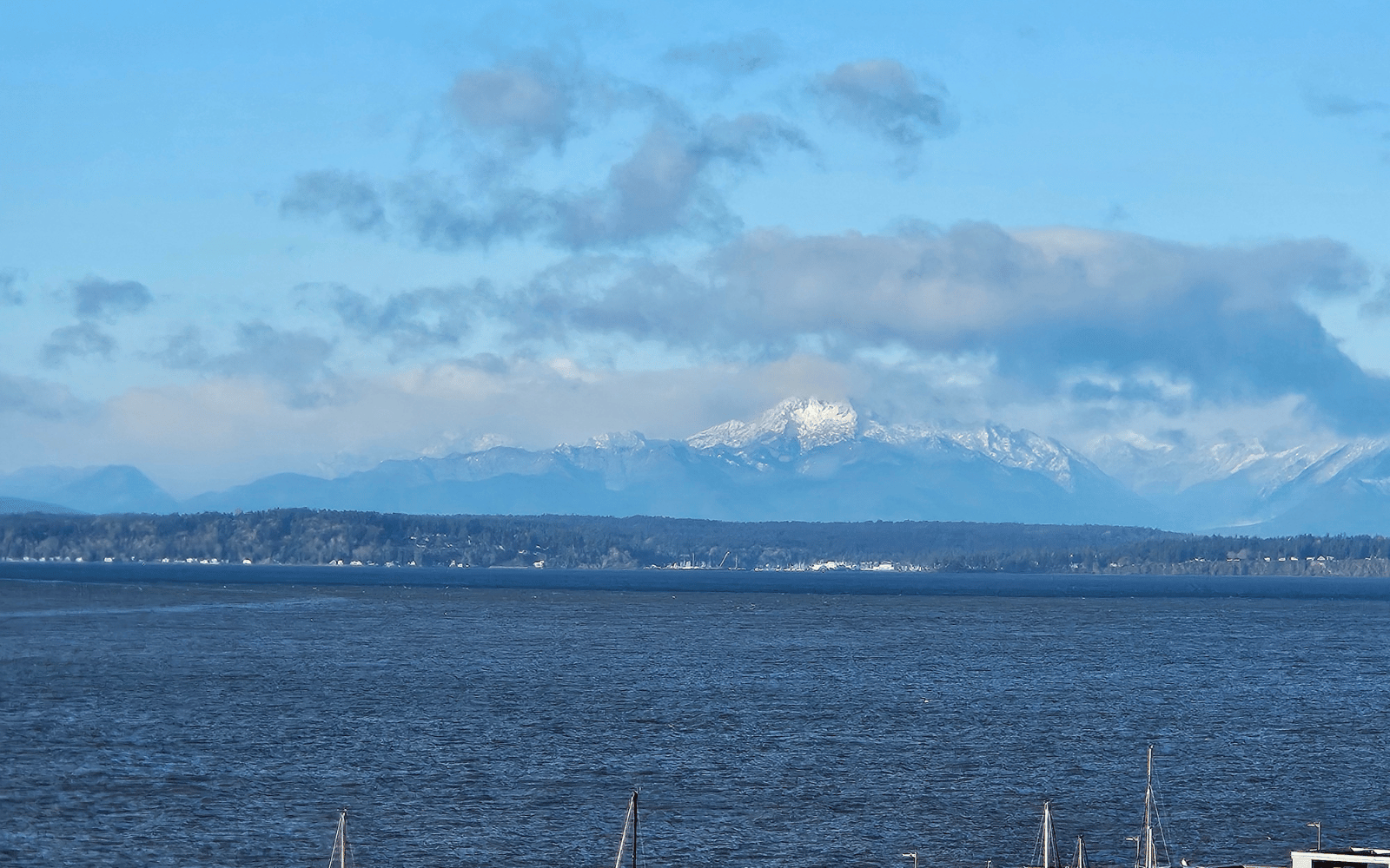 Brown water meets blue water with snow covered mountains behind.