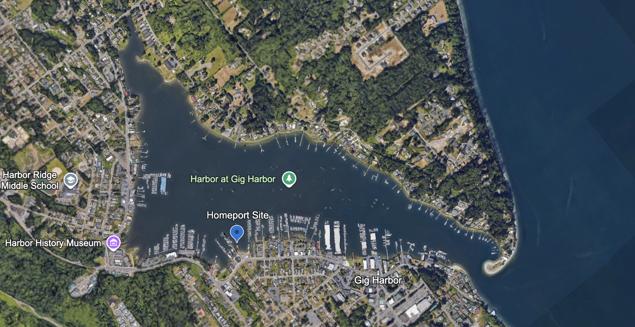 A satellite image a triangle-shaped harbor with a blue marker on the bottom shoreline.